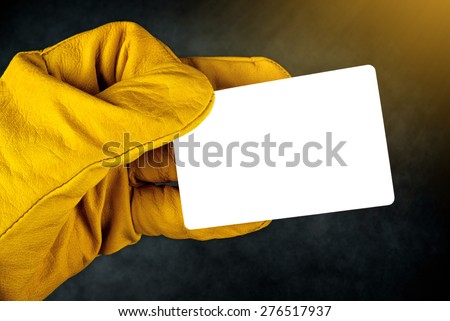 Male Hand in Yellow Leather Construction Working Protective Gloves Holding Horizontal Blank Business Card with Rounded Corners.