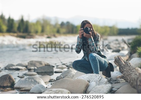 Young female photographer shooting, natural landscape on background