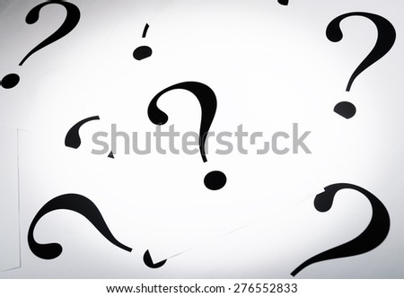 Printed question marks on the white paper spared on the table