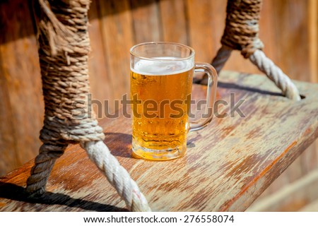 Mug of cold beer with foam on the swing. The Restaurant