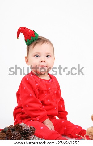 Funny baby dressed as a gnome on a white background. Happy child sitting next to a Christmas decoration. studio shooting