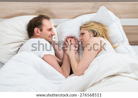 Loving Couple Looking At Each Other While Lying In Bed