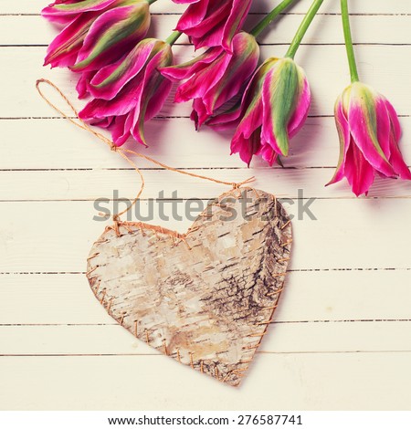 Fresh bright pink  tulips and rustic decorative heart  on white  painted wooden background. Selective focus. Place for text. Square image.