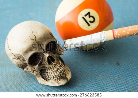 still life photography : skull with cigarette and number 13 pool game ball in temptation concept