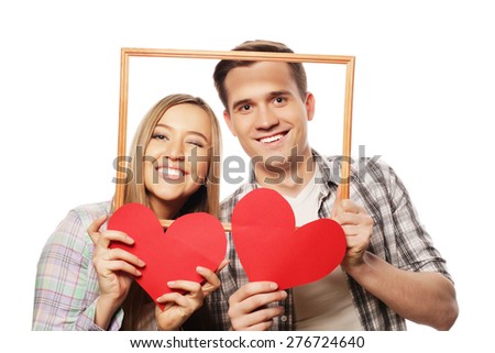 lovely couple holding frame and red hearts  over white background.