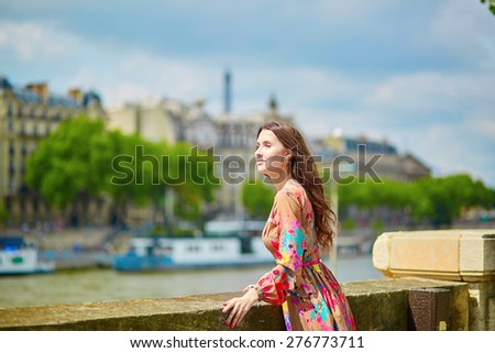 Young Parisian woman on the Seine embankment, the Eiffel tower in the background