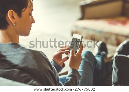 Young beautiful woman sitting with smart phone. Toned picture