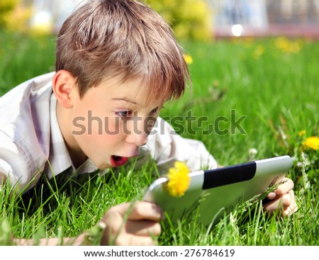Surprised Kid with Tablet Computer on the Summer Meadow