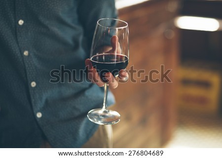 Young man holding a glass with red wine, bar on background Royalty-Free Stock Photo #276804689