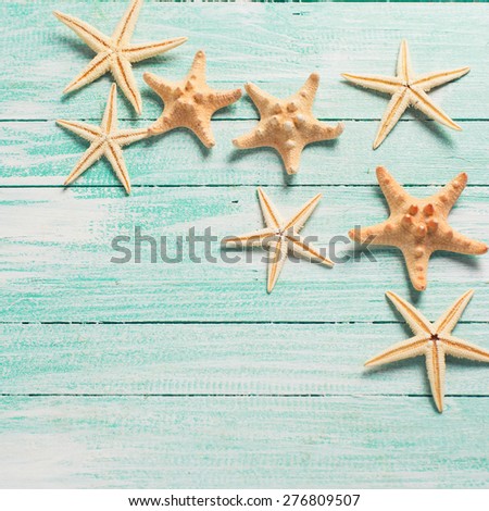 Marine items ( sea stars) on wooden background. Sea objects on turquoise painted wooden planks. Selective focus. Place for text. Square, toned image.