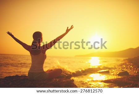 yoga at sunset on the beach. woman doing yoga, performing asanas and enjoying life on the sea Royalty-Free Stock Photo #276812570