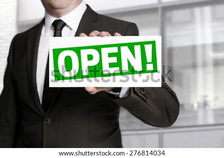 Businessman holding open sign to viewer.