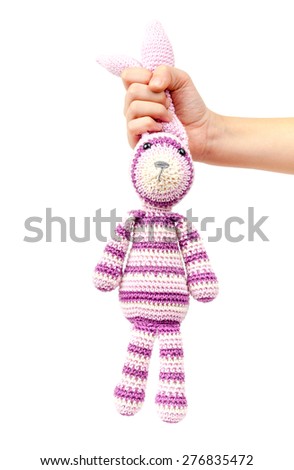 Child hand holds funny knitted rabbit toy isolated on white background