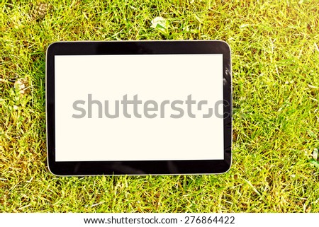 blank digital tablet lying on green grass
