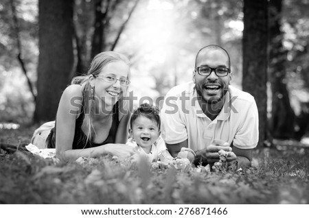 Happy interracial family is enjoying a day in the park. Little baby boy. Black and white B&W picture.