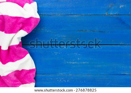 Blank rustic blue wooden beach sign with pink and white striped beach towel border; royal blue painted background with copy space