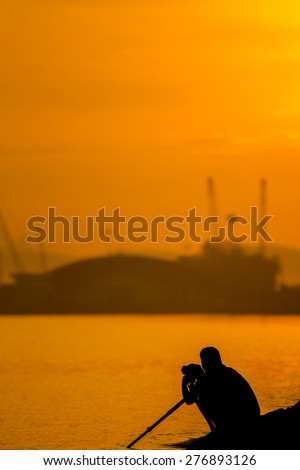 Photographer silhouette shooting sea outdoors on the rock 