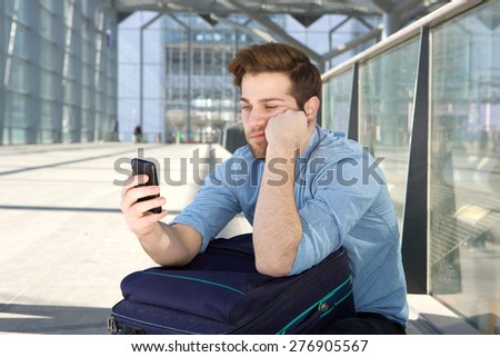 Portrait of a young man waiting at airport with bored expression on face