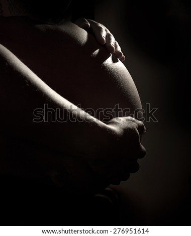 Close up of pregnant woman belly on the dark