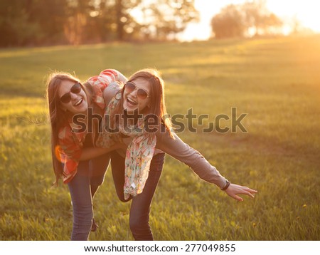Two young woman making fun on nature at sunset Royalty-Free Stock Photo #277049855