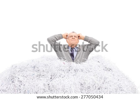 Senior man stuck in a pile of shredded paper, gesturing anger isolated on white background