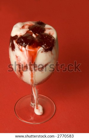 The glass with ice-cream with flow down strawberry jam over red background
