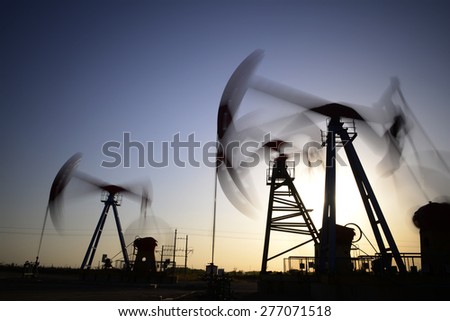 The setting sun is operation of the pumping unit in oil field 
