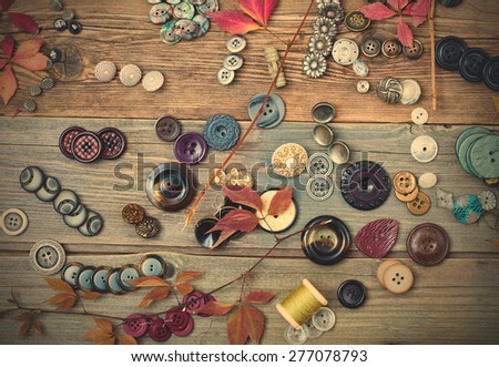 set of diverse vintage buttons with dried branches and leaves on the aged wooden boards. instagram image filter retro style
