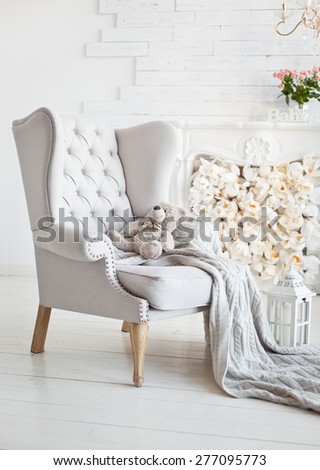 Elegant arm-chair with knitted blanket on it. Comfort interior in white color. Armchair with gray fabric upholstery Royalty-Free Stock Photo #277095773