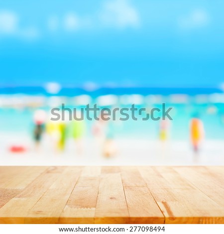 Wood table top with blurred people at the beach as background - can be used for display or montage your products
