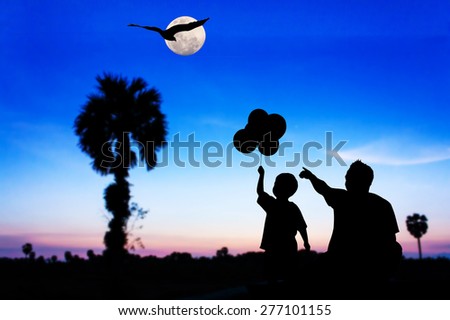 Silhouette  of father use hand point his son look at the full moon and eagle fly on the sky after sunset 
