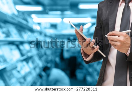 Businessman using the tablet on on Abstract blurred photo of book store with people background,blue color tone