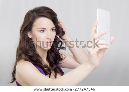 Brunette woman holding a cell phone, taking a photo of herself