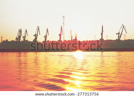 sea dock with tall cranes at sunrise, cross-processing effect