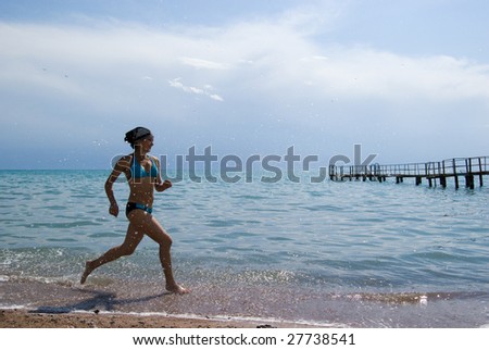 Photo of energetic female in swimsuit running along seashore during summer vacations