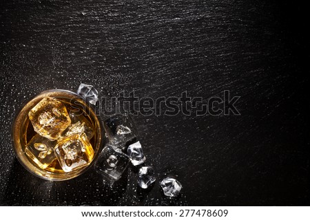 Glass of whiskey with ice on black stone table. Top view with copy space Royalty-Free Stock Photo #277478609