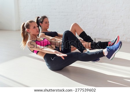 Side view of stretching at yoga class in fitness studio group of young women doing exercise abdominal crunches in the gym centre sport, training and lifestyle Royalty-Free Stock Photo #277539602
