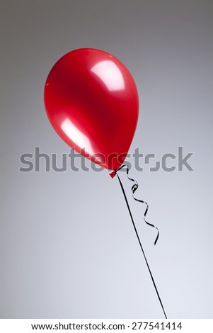 Single red balloon on a grey background 