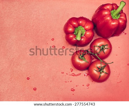 Ripe tomatoes and pepper on red cutting board with water drops
