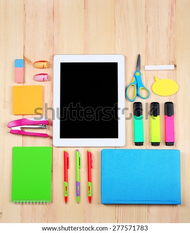 Digital tablet with stationery on wooden background