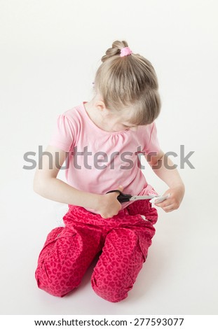 Little girl snipping off a brand label, white background