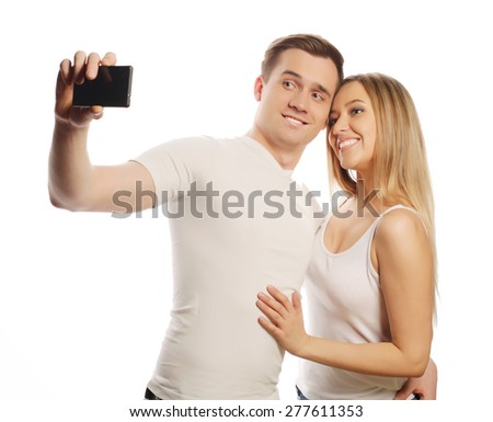 technology, love and friendship concept - smiling couple with smartphone, selfie and fun. Studio shot over white background. 