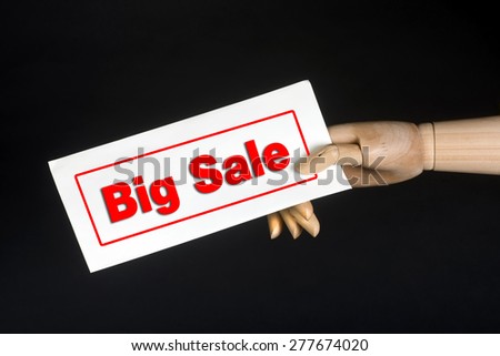 Big sale sign held by wooden hand.