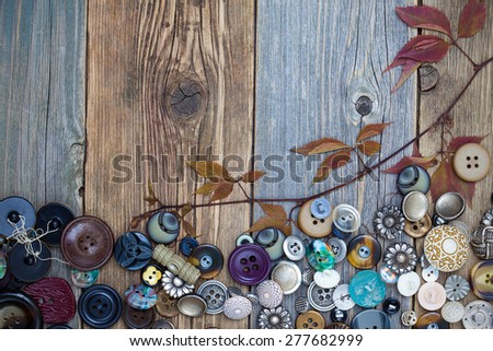 set of diverse vintage buttons with dried branches and leaves on the aged wooden boards