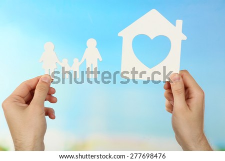 Female hands holding paper house and paper on turquoise background