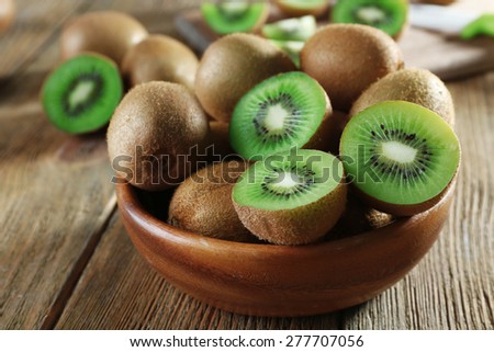 Juicy kiwi fruit in bowl on wooden table