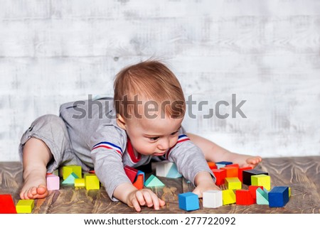 Cute baby boy is playing with colorful wooden bricks. Image with selective focus