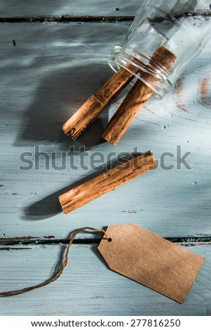 cinnamon sticks in a bottle with a blank label, on wooden background