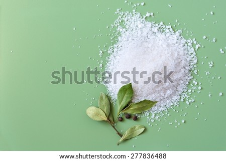 Sea salt heap and dried bay leaves on green background Royalty-Free Stock Photo #277836488