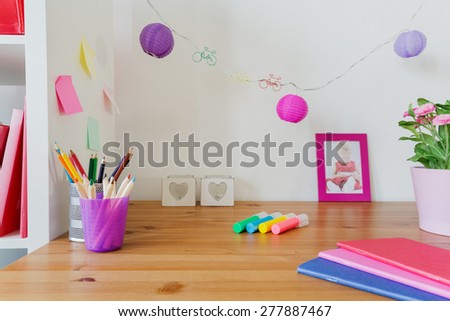 Color school accessories on the desk of little girl